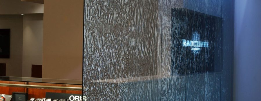 A banner showing the custom fabric laminated glass partition wall created for Radcliffe Jewelers by Archetype Glass